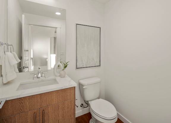 A white toilet sits next to a sink in a bathroom. at The Narrows at Clare Apartments , Washington, 98310
