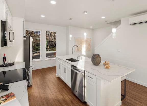 A modern kitchen with white cabinets and stainless steel appliances. at The Narrows at Clare Apartments , Washington, 98310