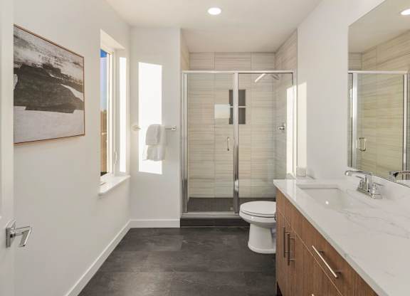 A bathroom with a toilet, sink, and shower. at The Narrows at Clare Apartments , Bremerton