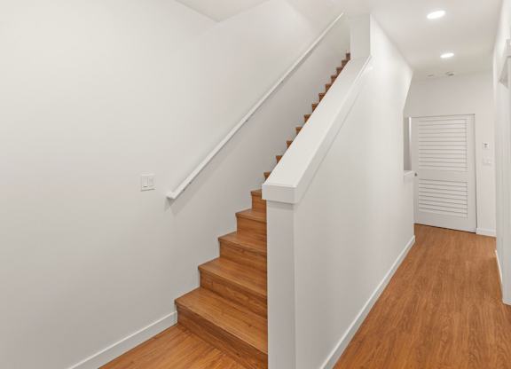 A wooden staircase with white walls and a white door. at The Narrows at Clare Apartments , Bremerton, WA, 98310