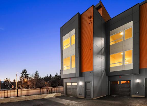 A modern building with orange and grey exterior and large windows at The Narrows at Clare Apartments , Bremerton, Washington
