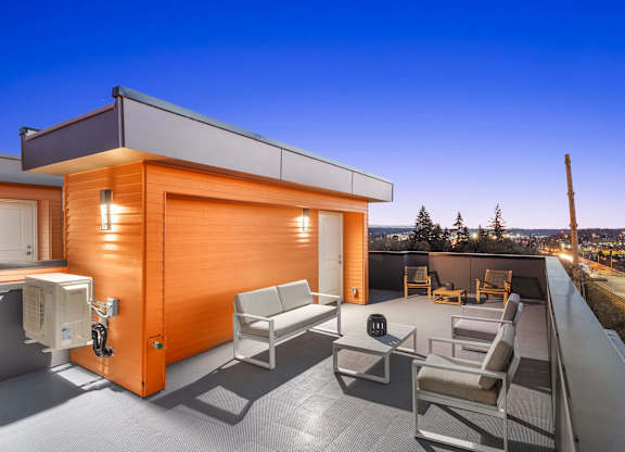 A modern house with a wooden exterior and a patio with chairs and a couch at The Narrows at Clare Apartments , Apartments, Bremerton, WA