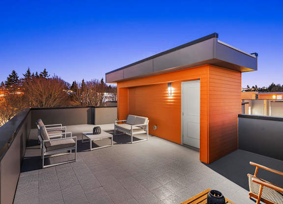A modern orange house with a patio and chairs at The Narrows at Clare Apartments , Bremerton, 98310