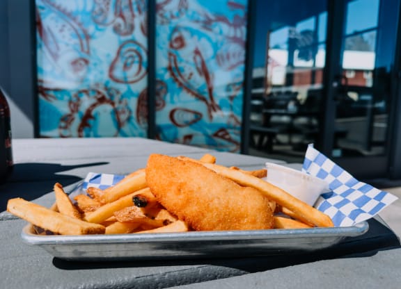 a plate of fish and chips on a table with graffiti in the background at Rivulet, Silverdale