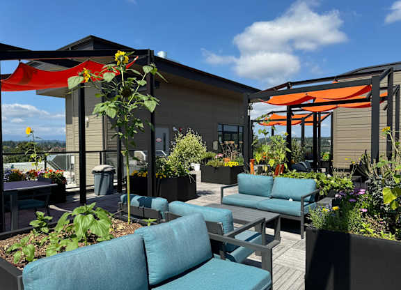 a rooftop patio with blue couches and orange umbrellas at Spyglass Hill Apartments, Bremerton, WA