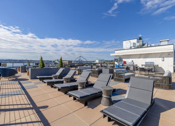 a roof top deck with lounge chairs and a barbecue at Marina Square, WA 98337