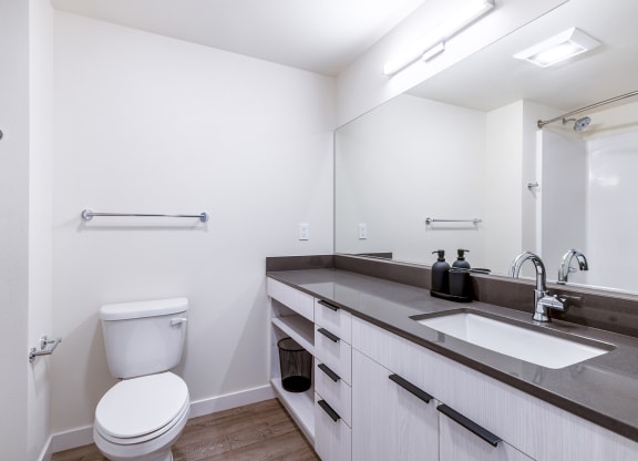 a bathroom with white walls and a large mirror at Marina Square, Bremerton