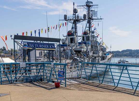 A large ship named USS Turner Joy is docked at a pier.