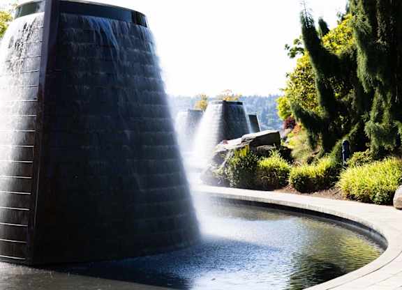 A water fountain with a tall, dark structure shooting water upwards.