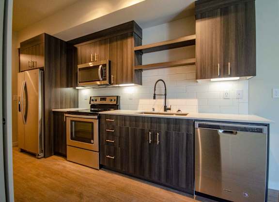 A modern kitchen with dark wood cabinets and stainless steel appliances at B Flats Apartments, Bremerton, Washington