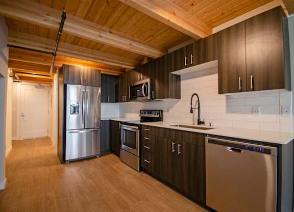 A kitchen with wooden cabinets and stainless steel appliances at B Flats Apartments, Washington 98337