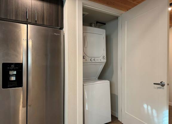 A stainless steel refrigerator is next to a white washing machine in a kitchen at B Flats Apartments, Bremerton, 98337