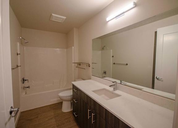 A white bathroom with a toilet, sink and bathtub at B Flats Apartments, Washington 98337