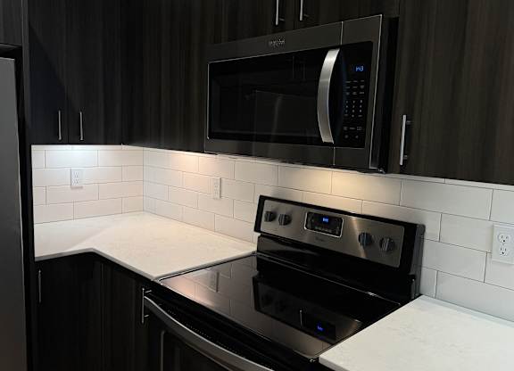 A modern kitchen with a black stove and microwave above it at B Flats Apartments, Bremerton, WA, 98337