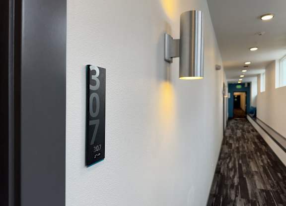 A hallway with a wall-mounted light fixture and a sign that reads at B Flats Apartments, Bremerton, 98337