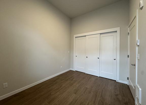 A room with white walls and wood flooring with a white door at B Flats Apartments, Bremerton, Washington