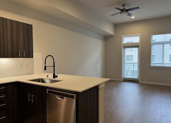 A modern kitchen with dark wood cabinets and a stainless steel dishwasher at B Flats Apartments, Bremerton