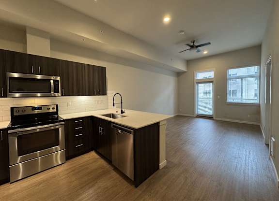 A modern kitchen with dark wood cabinets and stainless steel appliances at B Flats Apartments, Washington
