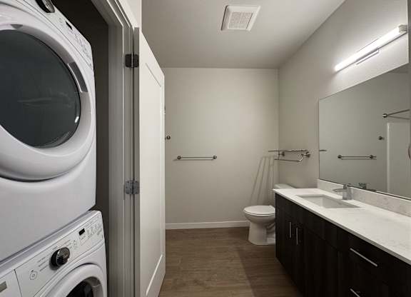 A white washing machine is in a small laundry room with a toilet and sink at B Flats Apartments, Bremerton, WA