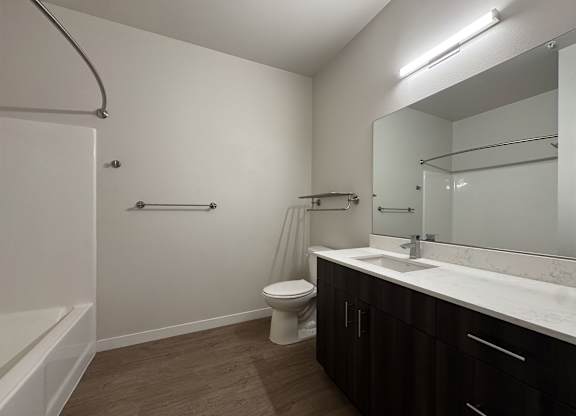 A bathroom with a toilet, sink, and mirror at B Flats Apartments, Bremerton, 98337