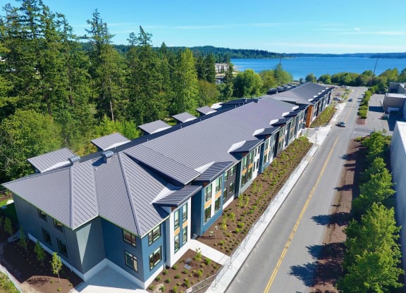 an aerial view of a building with a metal roof and a lake in the background at Rivulet, Silverdale, 98383