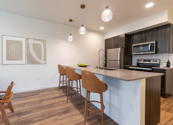 a kitchen with a large island with three stools in front of a counter top at Rivulet, Silverdale, WA