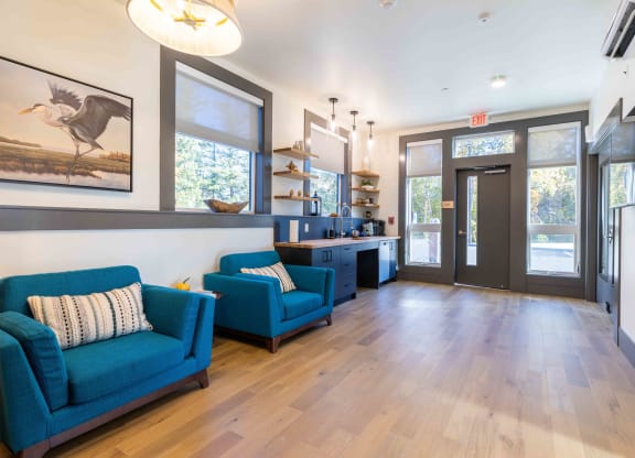 a living room with blue couches and a kitchen with a large window at Rivulet, Silverdale, 98383