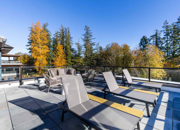 a patio with chairs and tables on a balcony with trees at Rivulet, Silverdale, 98383
