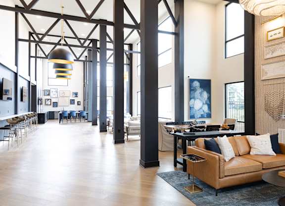 Industrial loft style lobby with exposed beams and leather sofa at The Crest at South Point Apartments, McDonough, Georgia