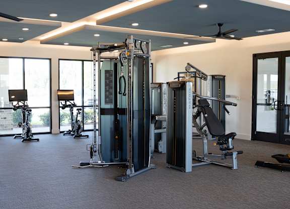A gym with a variety of equipment including a squat rack, a leg press machine, and a bench press.