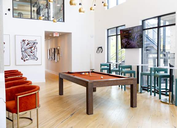 A room with a pool table and chairs.