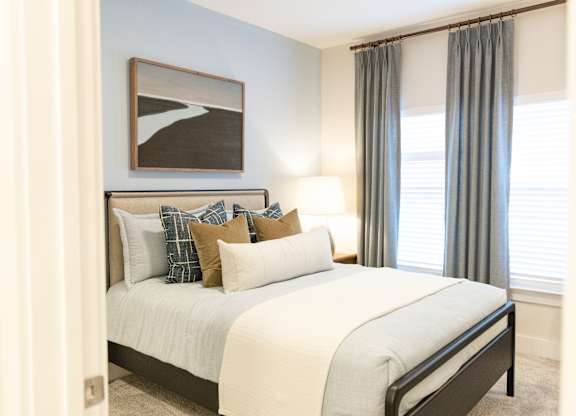 Secondary bedroom with a stages bed and large window in a two-bedroom model apartment at The Crest at Oakwood in Oakwood, GA.