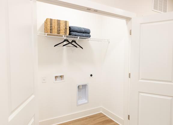 Laundry closet with washer and dryer hookups and overhead shelving in a two-bedroom apartment at The Crest at Oakwood in Oakwood, GA.