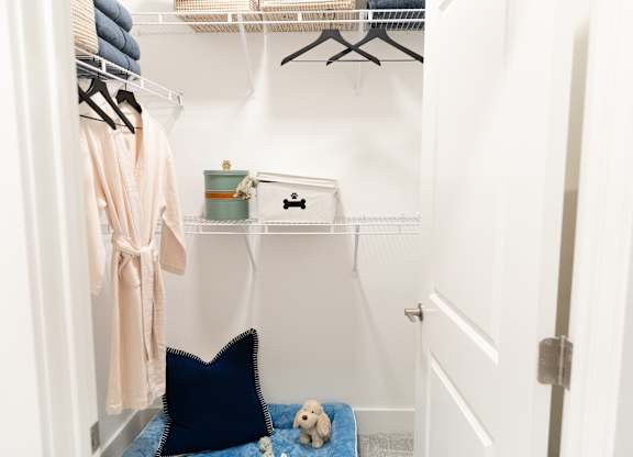 Primary bedroom walk-in closet with shelving and hanging space in a two-bedroom model apartment at The Crest at Oakwood in Oakwood, GA.