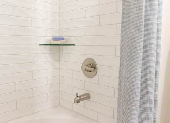 Close-up of the tiled tub and shower surround with chrome fixtures in a two-bedroom model apartment at The Crest at Oakwood in Oakwood, GA.