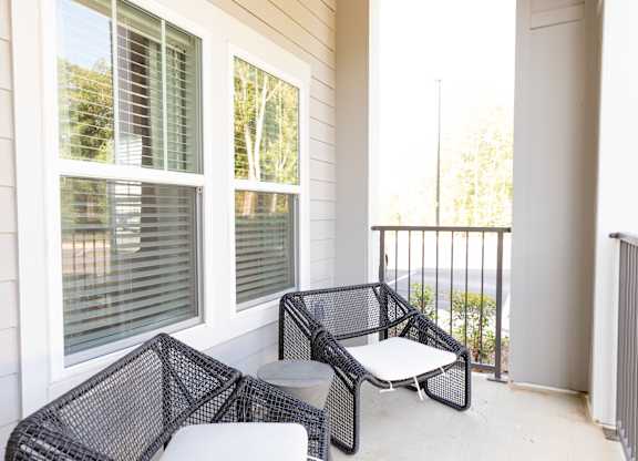 Patio with outdoor seating and a railing at a two-bedroom model apartment at The Crest at Oakwood in Oakwood, GA.