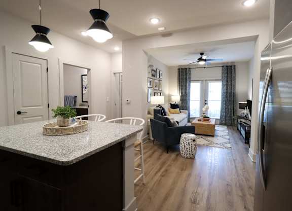 Open concept kitchen and living room with island seating at The Crest at South Point Apartments, McDonough, 30253