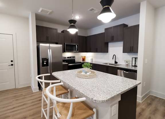 Modern kitchen with island seating and dark cabinetry at The Crest at South Point Apartments, McDonough, GA