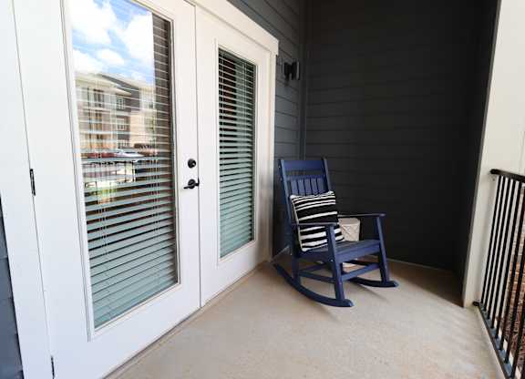 Private balcony with rocking chair and striped pillow at The Crest at South Point Apartments, Georgia, 30253