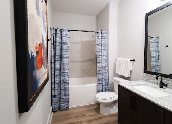 Bathroom with wood flooring and granite countertop vanity at The Crest at South Point Apartments, McDonough, GA
