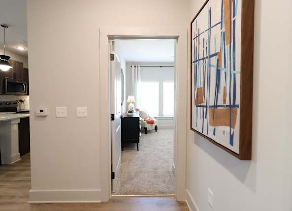 Hallway view into carpeted bedroom with seating area at The Crest at South Point Apartments, McDonough, 30253