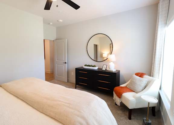 Bedroom with dresser and round mirror at The Crest at South Point Apartments, McDonough, 30253
