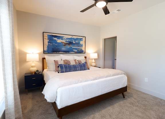 Bedroom with ceiling fan and striped accent pillows at The Crest at South Point Apartments, Georgia, 30253