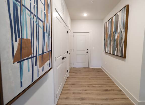 Entryway hallway with abstract artwork and wood flooring at The Crest at South Point Apartments, McDonough, GA 30253