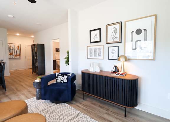 Living room with navy accent chair and gallery wall at The Crest at South Point Apartments, McDonough