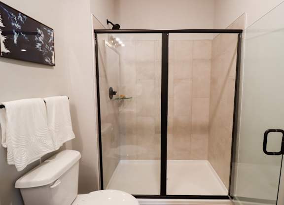 Modern bathroom with sliding glass shower doors at The Crest at South Point Apartments, Georgia, 30253