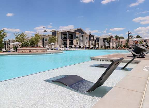 Resort style pool with tanning ledge and lounge chairs at The Crest at South Point Apartments, McDonough, GA 30253