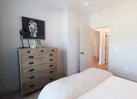 Bedroom with wooden dresser and wall mounted artwork at The Crest at South Point Apartments, McDonough