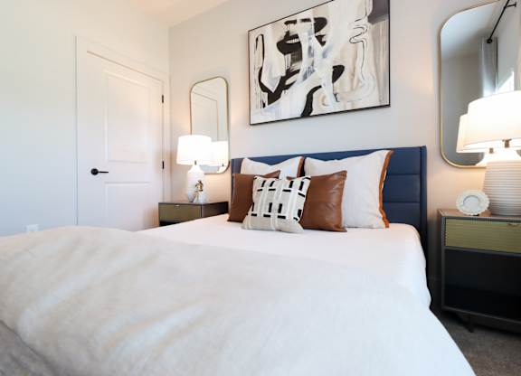 Bedroom with navy upholstered headboard and decorative pillows at The Crest at South Point Apartments, McDonough, GA