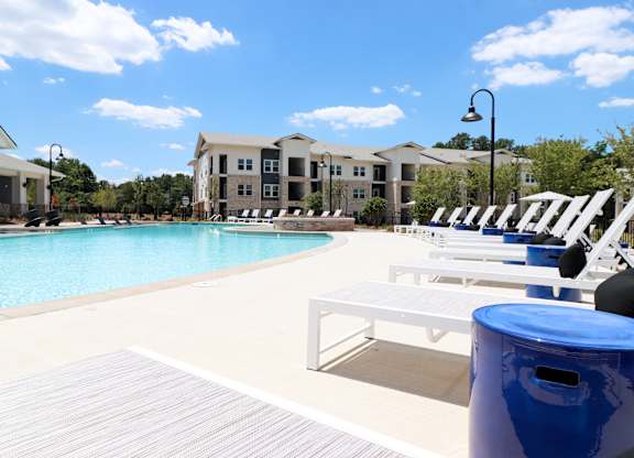 Swimming pool with sundeck and decorative blue side tables at The Crest at South Point Apartments, Georgia